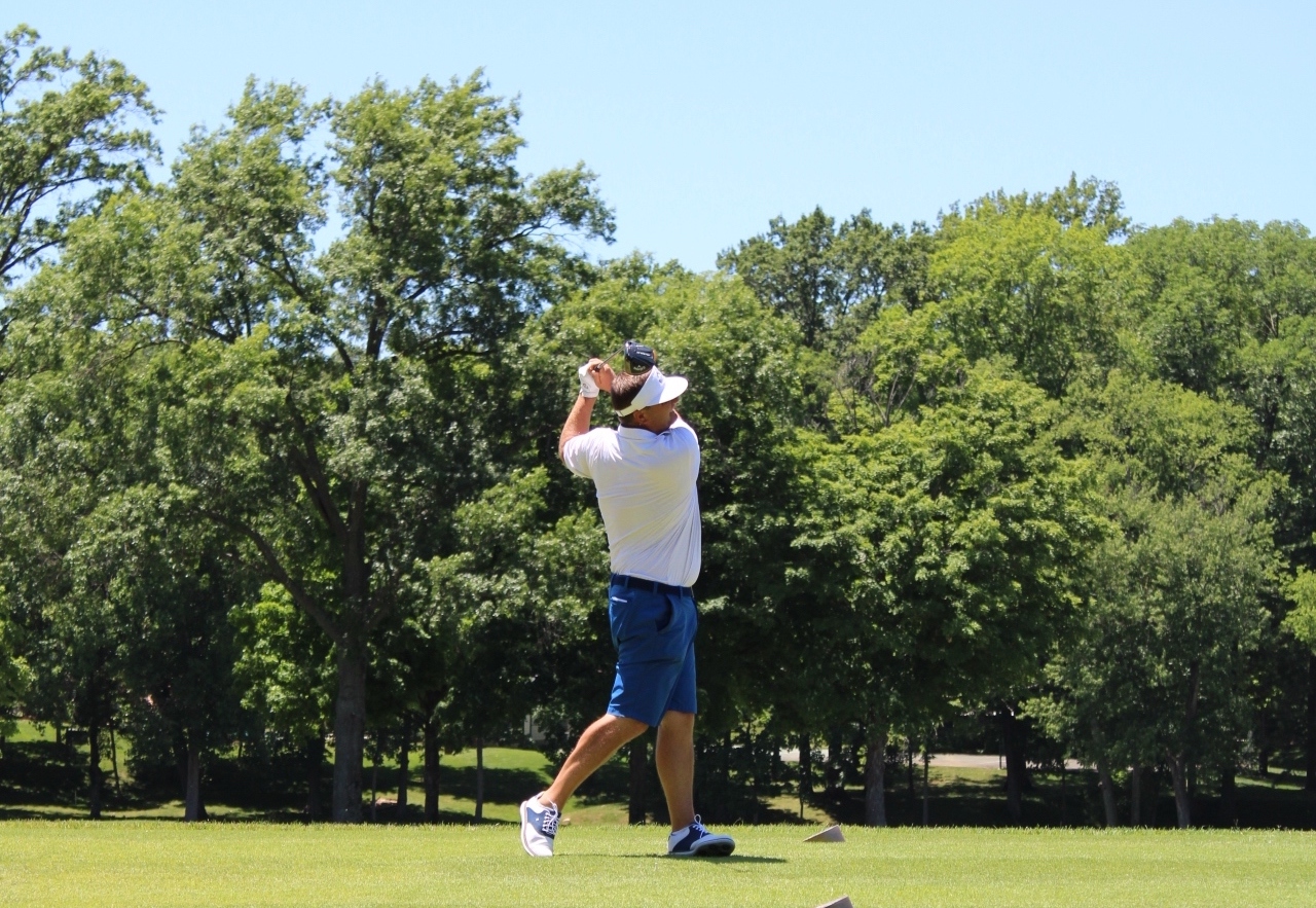 woman tees off at a golf course